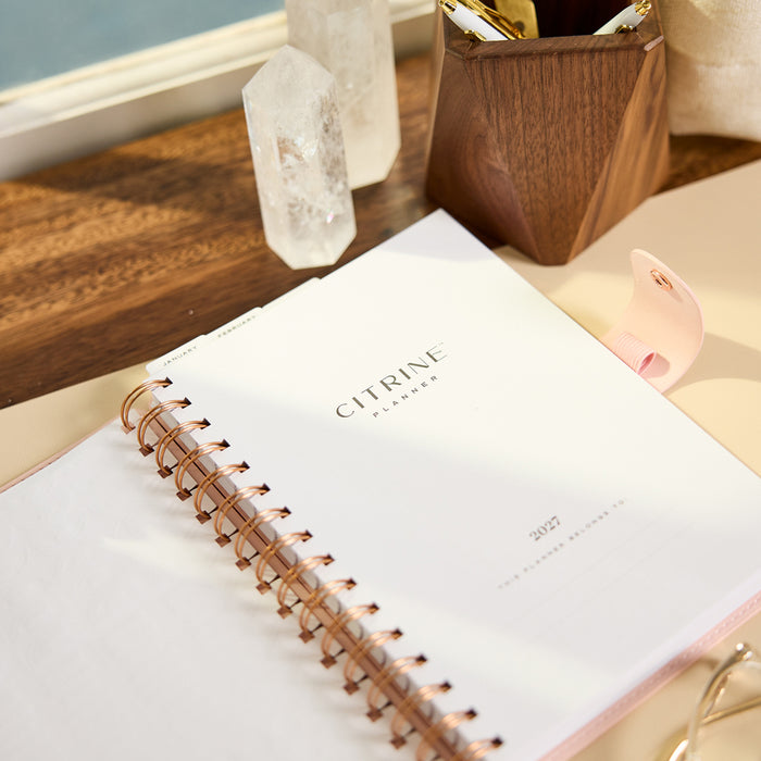 2027 Blush Diagonals Customizable Spiral Citrine Planner - Small Professional Layout - 12 Months shown on a desk with copper spiral binding and white cover