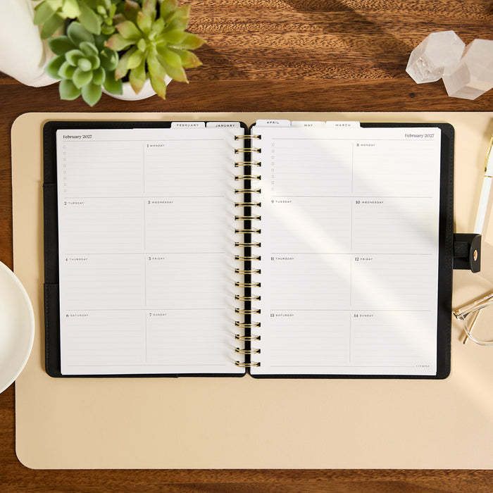 2027 Midnight Customizable Spiral Citrine Planner - Classic Professional Layout - 12 Months open to a February 2027 monthly spread on a desk