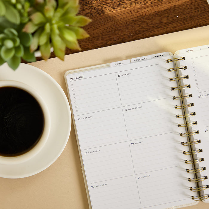 2027 Notes & Plans Customizable Spiral Citrine Planner - Small Professional Layout - 12 Months open to a weekly spread beside coffee and a succulent on a wood desk