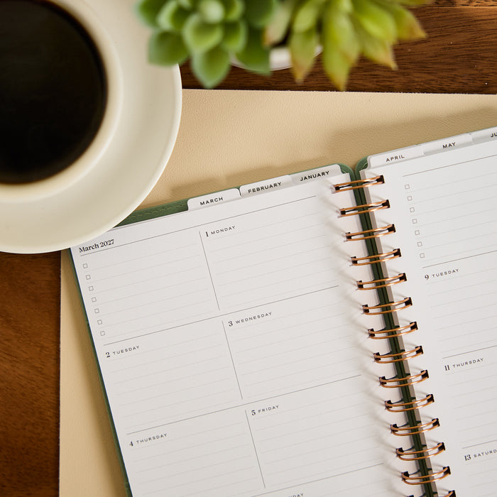 2027 Sage Waves Customizable Spiral Citrine Planner - Small Professional Layout - 12 Months open to a weekly planning spread with spiral binding on a wooden desk