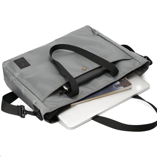 Gray laptop bag with black straps holding a laptop and notebook on white background
