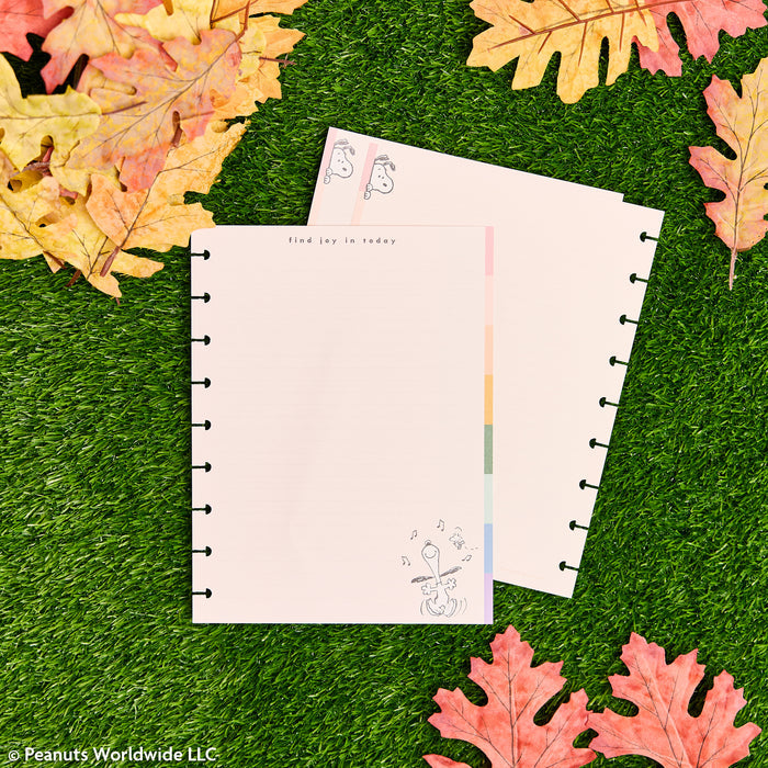 PEANUTS™ - Dotted Lined Classic Filler Paper - 40 Sheets with pastel lined pages and disc punched edges displayed on green grass with autumn leaves