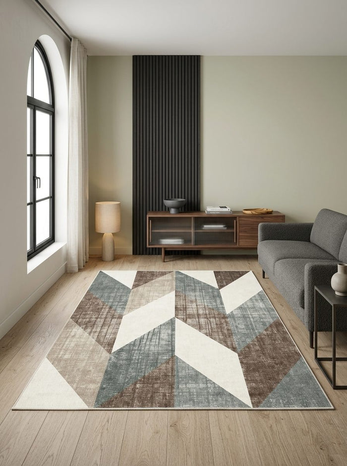 Blue, brown, and cream geometric chevron rug in a modern living room with wood floors and a grey sofa.