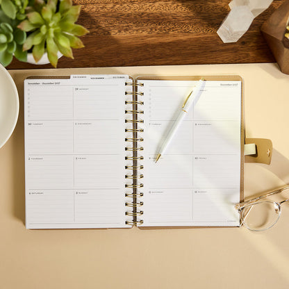 2027 Ivory Delicate Dots Customizable Spiral Citrine Planner - Small Professional Layout - 12 Months open on a desk with pen and glasses