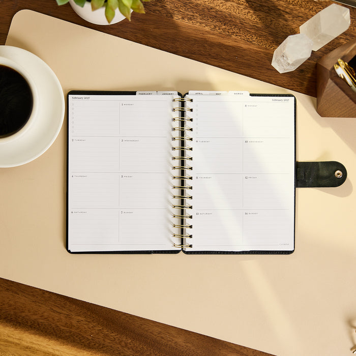 2027 Midnight Micro Dots Customizable Spiral Citrine Planner - Small Professional Layout - 12 Months open to a clean monthly planning spread on a desk