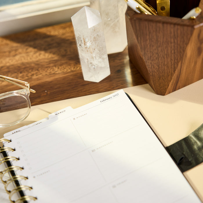 2027 Midnight Micro Dots Customizable Spiral Citrine Planner - Small Professional Layout - 12 Months open on a wooden desk with crystal decor and glasses