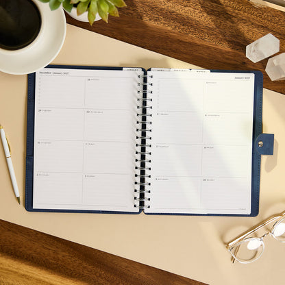 2027 Navy Customizable Spiral Citrine Planner - Classic Professional Layout - 12 Months open to a two-page monthly spread with spiral binding on a desk