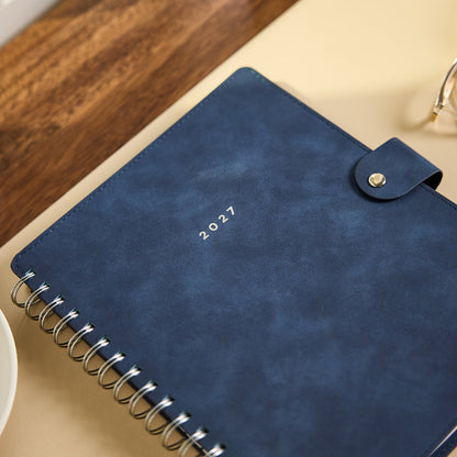 2027 Navy Customizable Spiral Citrine Planner - Classic Professional Layout - 12 Months with navy cover and silver spiral binding on a desk