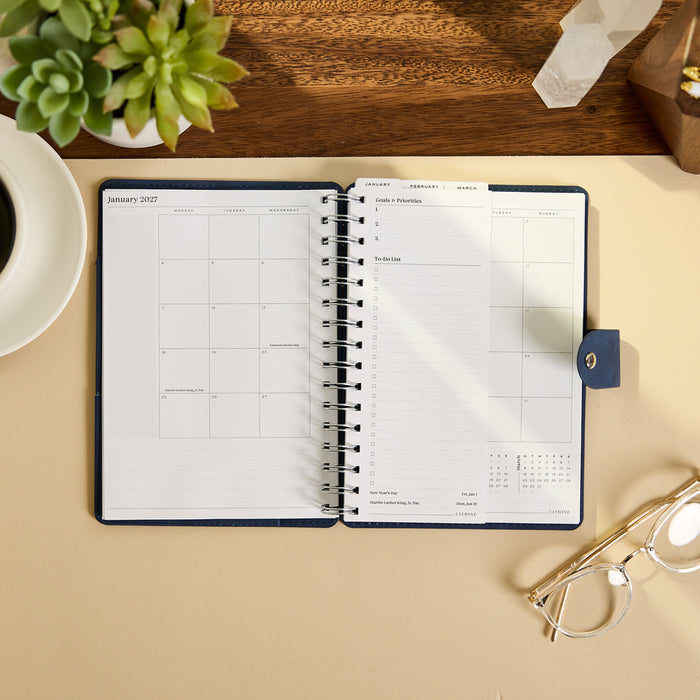 2027 Navy Customizable Spiral Citrine Planner - Small Professional Layout - 12 Months open on a desk showing monthly and weekly planning pages