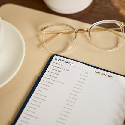 2027 Navy Herringbone Customizable Spiral Citrine Planner - Small Professional Layout - 12 Months showing a 2027 holidays and special dates page beside eyeglasses