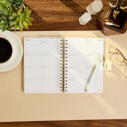 2027 Notes & Plans Customizable Spiral Citrine Planner - Small Professional Layout - 12 Months open on a desk with weekly planning pages and pen