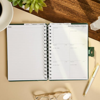 2027 Sage & Scallop Customizable Spiral Citrine Planner - Small Professional Layout - 12 Months open to notes and quarterly priorities and projects pages on a desk
