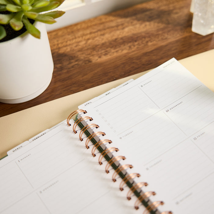 2027 Sage Waves Customizable Spiral Citrine Planner - Small Professional Layout - 12 Months open with organized monthly and weekly planning pages on a wooden desk