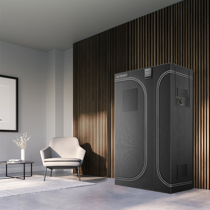 Black AC Infinity Cloudlab 743D multi-chamber grow tent for indoor plants, standing in a modern living room.