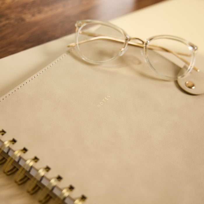Citrine - Mocha - Classic Customizable Spiral Notebook with a mocha cover and gold spiral binding, photographed with eyeglasses resting on top