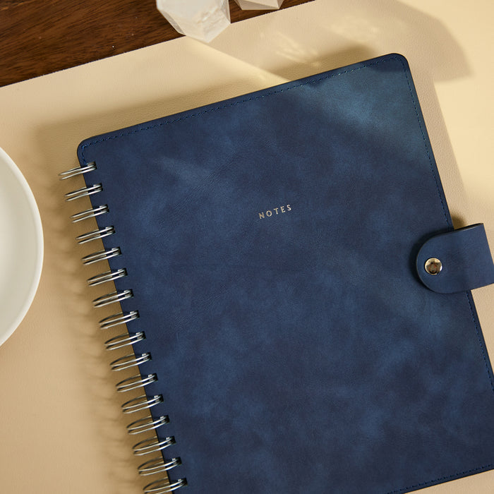 Citrine - Navy - Classic Customizable Spiral Notebook with a navy cover gold spiral binding and snap closure on a desk