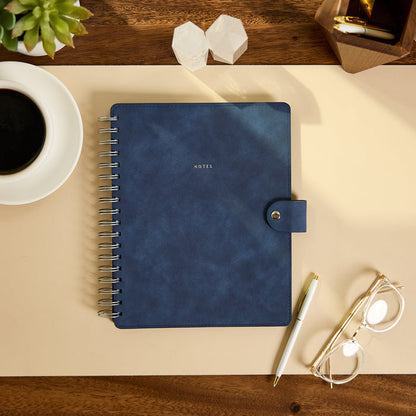 Citrine - Navy - Classic Customizable Spiral Notebook with gold spiral binding and snap closure on a desk beside a pen coffee cup and eyeglasses