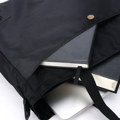 Black tote bag with notebook, book, and laptop partially visible inside