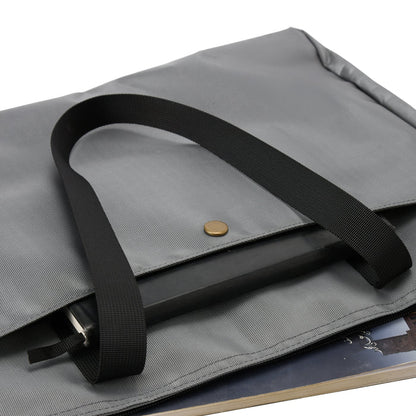 Gray fabric laptop bag with black strap, button closure and book inside