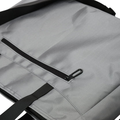 Close-up of a gray fabric tote bag with black zipper pocket and strap