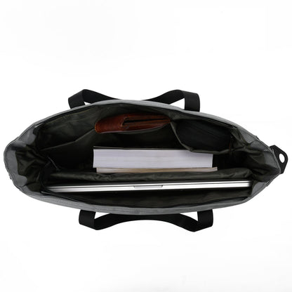 Open top view of a black tote bag with laptop, notebook, and accessories neatly organized inside.