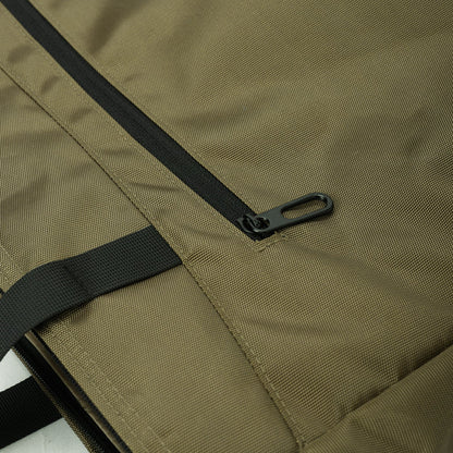 Close-up of khaki travel bag with black zipper and strap detail