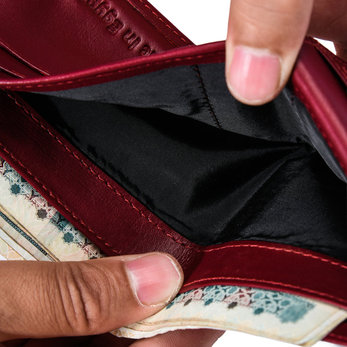 Close-up of a person opening a Burgundy leather wallet with patterned trim and black interior.