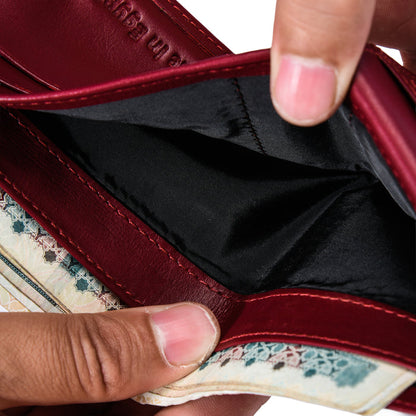 Close-up of a person opening a Burgundy leather wallet with patterned trim and black interior.