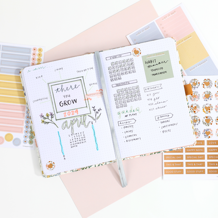 Open Ditsy Wildflower - Bullet Dot Grid Happy Journal® - 80 Sheets - 160gsm Paper showing an April monthly planner spread with habit tracker, colorful stickers, and handwritten notes on a pastel background