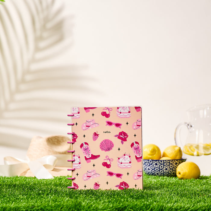 Happy Little Vibes - Dotted Lined Classic Notebook - 60 Sheets with pink summer-themed cover featuring sunglasses, cherries, and seashells, standing on grass with lemon pitcher and straw hat in background.