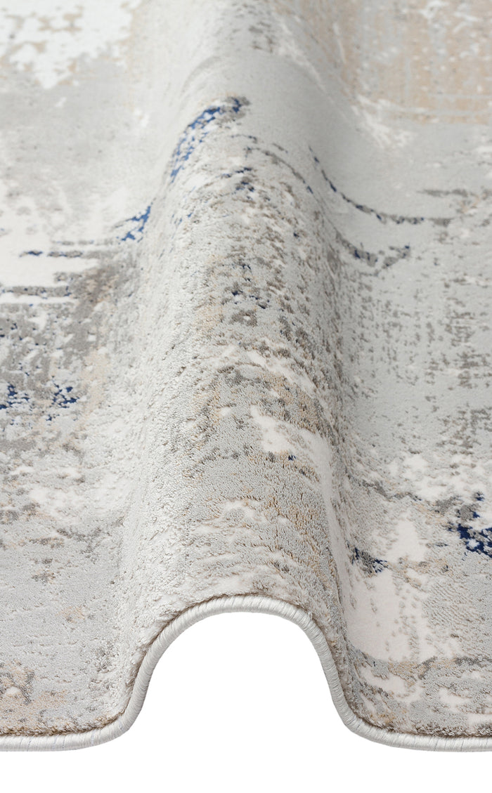 Grey, white, and blue abstract distressed rug with a folded edge on a white background.