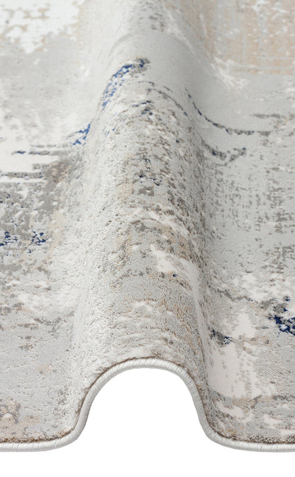 Grey, white, and blue abstract distressed rug with a folded edge on a white background.