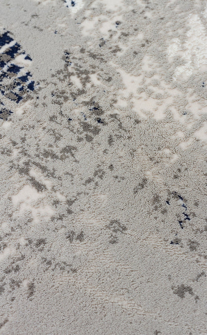Close-up of a high-pile rug with a distressed, abstract pattern in shades of grey, cream, and navy blue.