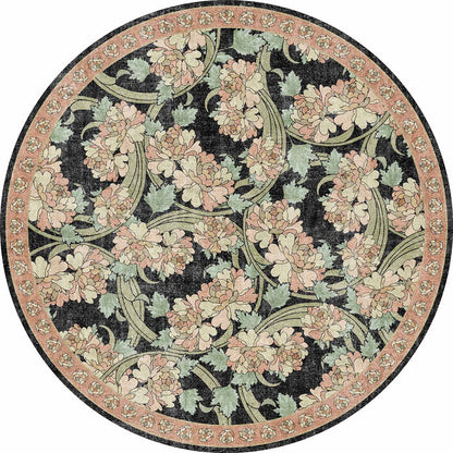 Round rug with a black background, featuring a floral pattern of pink peonies and sage green leaves with a floral border.