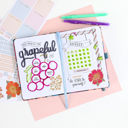 Open Retro Blooms - Bullet Dot Grid Happy Journal® - 80 Sheets - 160gsm Paper with hand-drawn gratitude list, calendar, and floral doodles, next to pastel stickers and colorful pens.