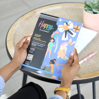 Person holding the Squad Goals Love Every Season - Large Value Pack Stickers pack featuring colorful illustrated stickers of people, flowers, and gifts, designed for Happy Planner and disc bound planners.