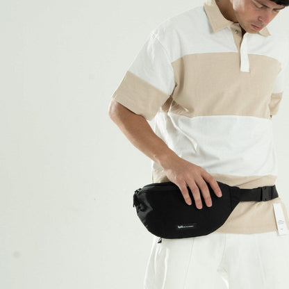 Man wearing black waist pack crossbody bag over beige and white collared shirt