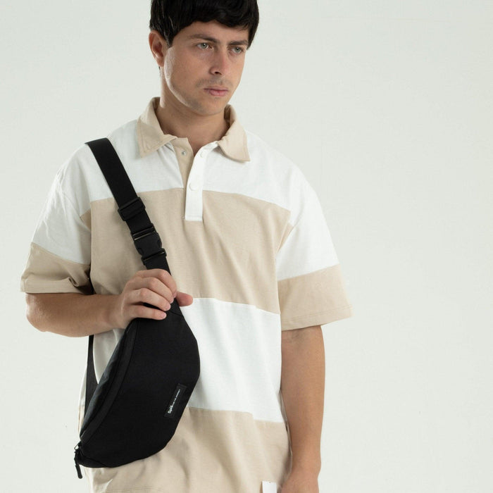 Man wearing black cross bag waist pack fanny pack with adjustable strap on beige striped shirt