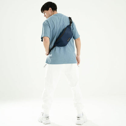 Man wearing blue crossbody fanny pack with adjustable strap, casual outfit, white background