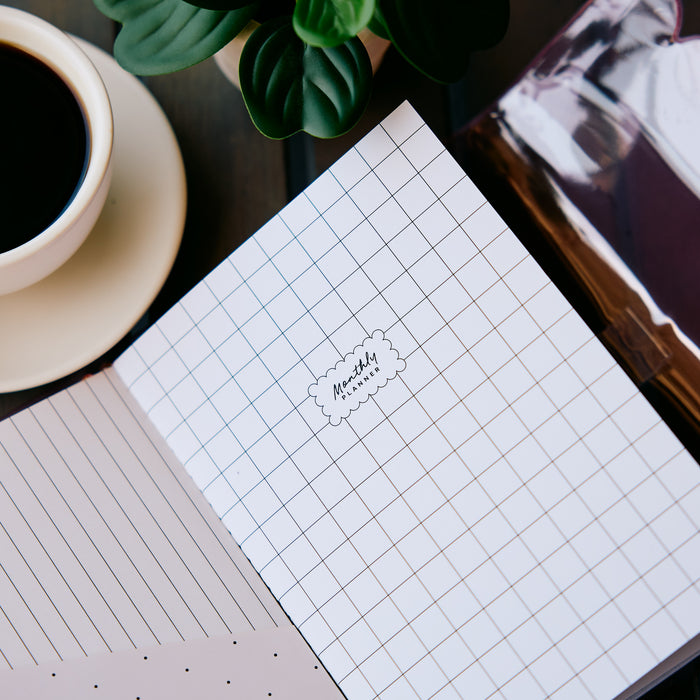 Undated Modern Tones Folio Planner Insert - Monthly Calendar View A5 Layout- 12 Months shown as a grid page beside lined paper coffee and greenery