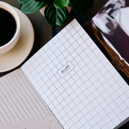 Undated Modern Tones Folio Planner Insert - Monthly Calendar View A5 Layout- 12 Months shown as a grid page beside lined paper coffee and greenery