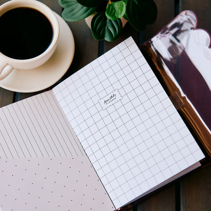Undated Modern Tones Folio Planner Insert - Monthly Calendar View A5 Layout- 12 Months with grid lined and dotted pages beside coffee and a leafy plant