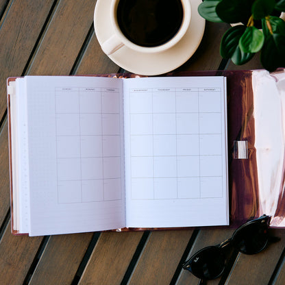 Undated Modern Tones Folio Planner Insert - Monthly Calendar View A5 Layout- 12 Months open to a monthly calendar spread beside coffee and sunglasses