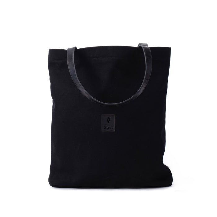 Black canvas tote bag with leather handles and front patch on white background