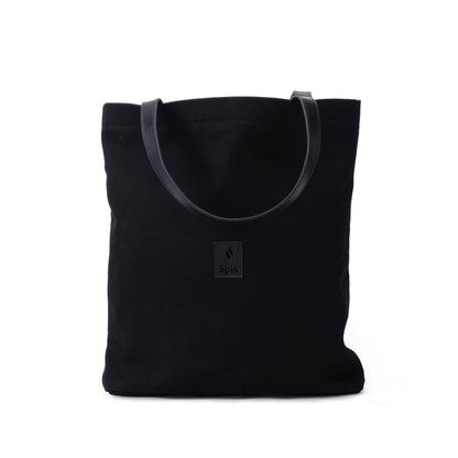 Black canvas tote bag with leather handles and front patch on white background