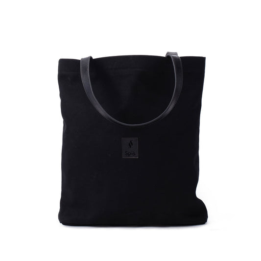 Black canvas tote bag with leather handles and front patch on white background