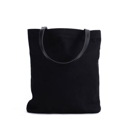 Black canvas tote bag with leather straps on white background