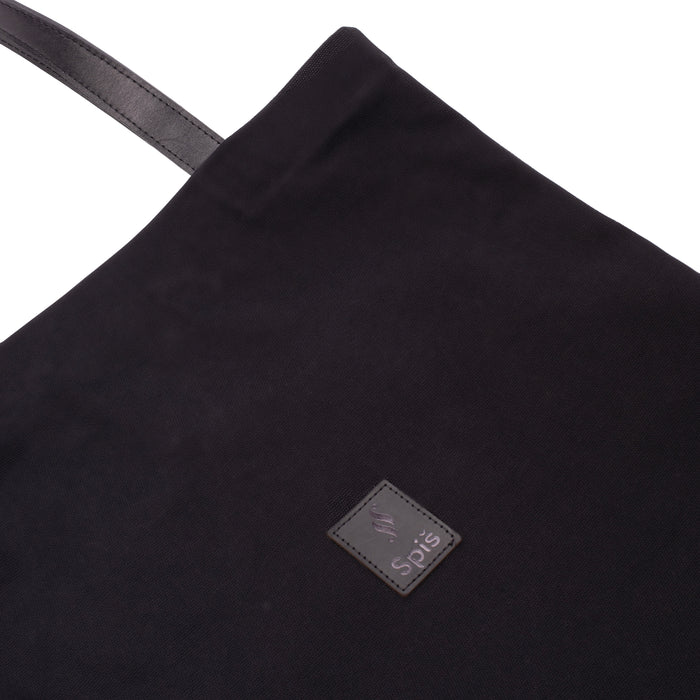 Black canvas tote bag with leather handle and stitched logo patch