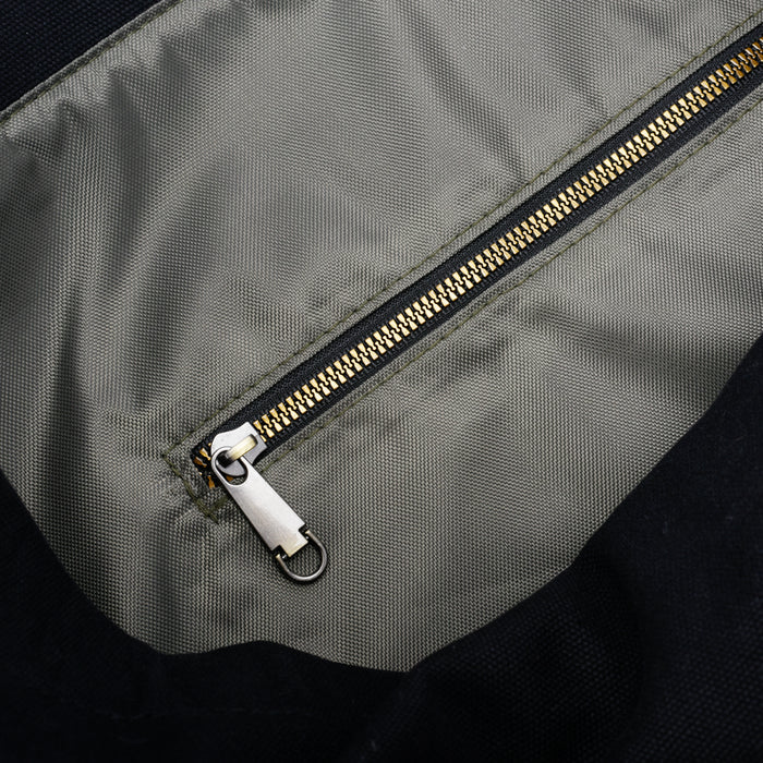 Close-up of a gray fabric bag interior with a gold zipper pocket