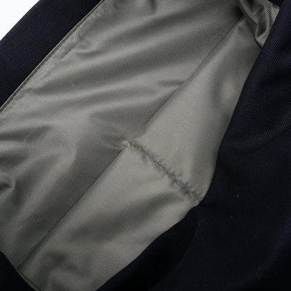 Close-up of grey fabric bag lining with a stitched pocket detail